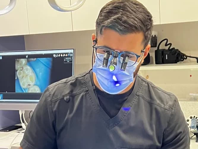 A Dental Works dentist examining a patient using magnifying loupes